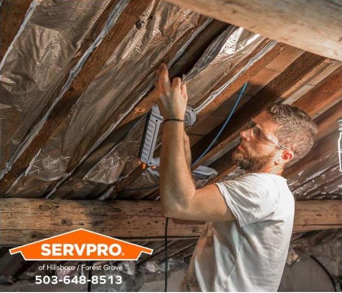 A person is adding insulation to the ceiling in his attic.