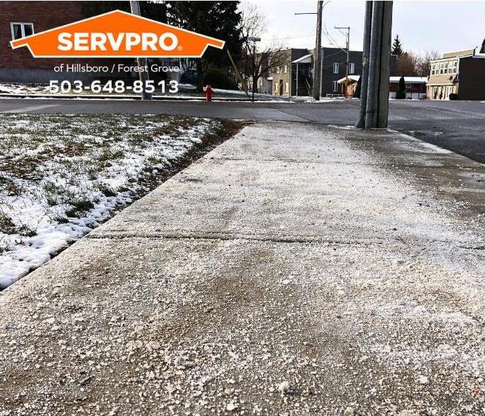 A sidewalk has a light dusting of snow from a recent storm.